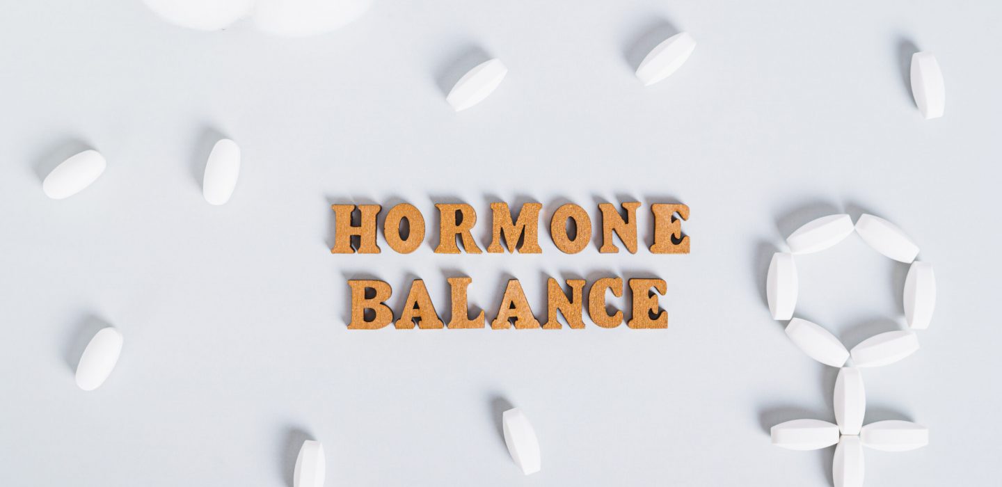 Hormonal balance concept, pills around text on blue background top view